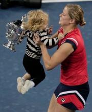 Kim Clijsters picks up her daughter while holding her 2009 US Open trophy.JPG
