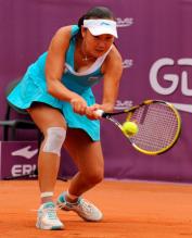 Peng Shuai in a cyan tennis dress hits a two handed shot at the French Open 2011.JPG