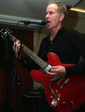 John McEnroe sings and plays a guitar.jpg